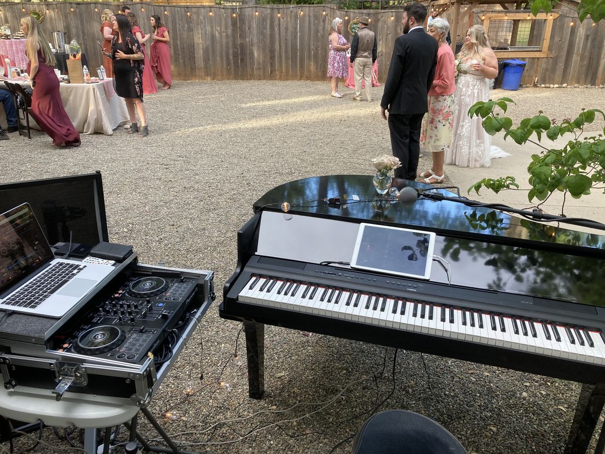 DJ controller flight case beside a digital grand piano at a wedding