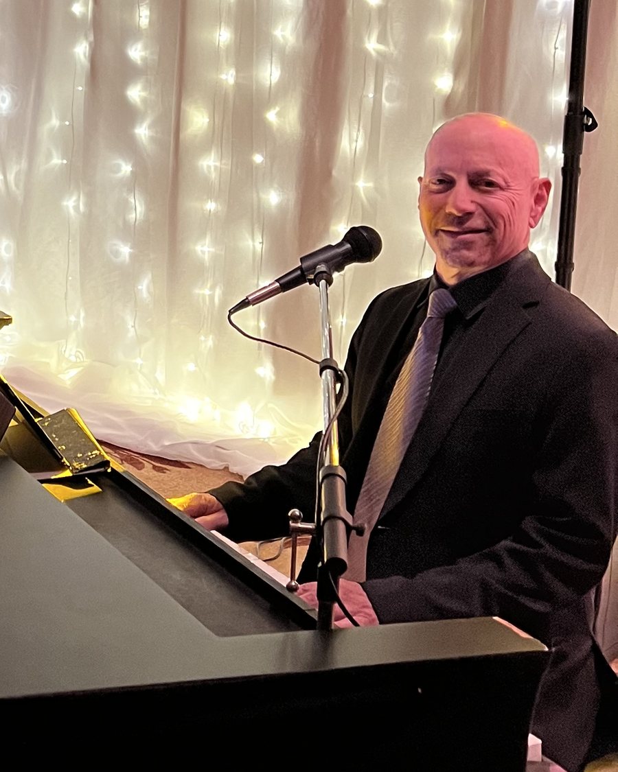 Joel Nelson performing at a grand piano at a dueling-pianos event